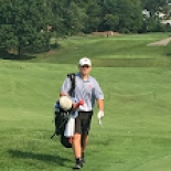 Male golfer walking with bag