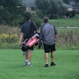 Male golfers walking across green